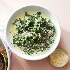 a white bowl filled with broccoli and cheese next to a container of soup