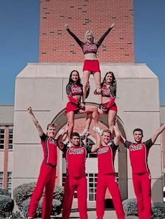 a group of cheerleaders standing on top of each other in front of a building