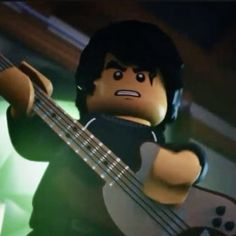 a lego man with headphones and a guitar in front of his face, playing the bass