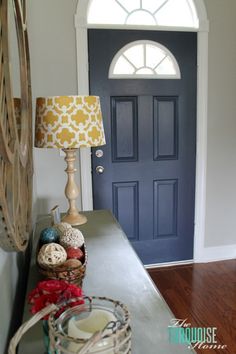 a blue front door with a lamp and some balls on the table next to it