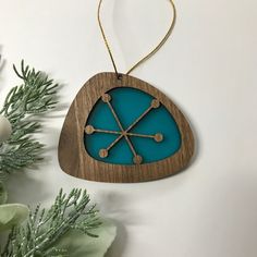 a wooden ornament hanging from a tree branch with blue and brown decorations on it