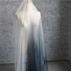 a white and blue dress on display in front of a gray wall with a mannequin's head