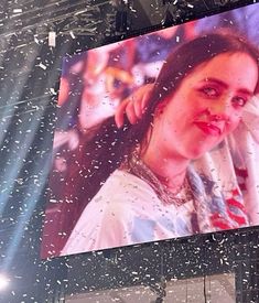 a large billboard with a woman's face on it and snow falling all around