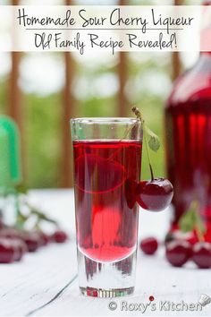 a glass filled with cherries sitting on top of a table