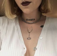 a woman with a wine glass tattoo on her chest and neck is wearing a white shirt