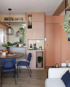 a living room and dining area are shown with pink walls, blue chairs, and wood flooring