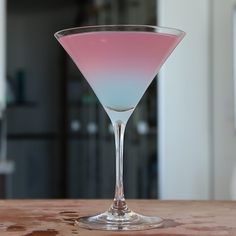 a pink and blue drink sitting on top of a wooden table