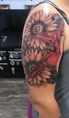 a woman's arm with sunflowers and red birds on the back of it