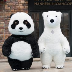 two large white and black teddy bears standing next to each other in front of a building