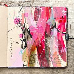 an open notebook with colorful designs on it sitting on a wooden table next to a pen