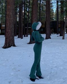 a person in a green jumpsuit standing in the snow