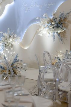 a room filled with white chairs and tables covered in frosted glass vases next to a sign that says, my wedding is you