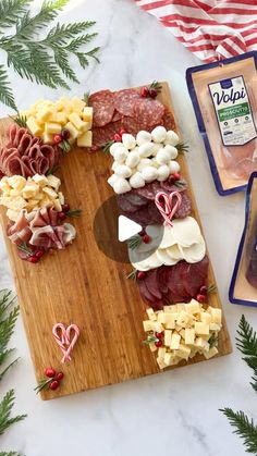 an assortment of meats and cheeses on a cutting board next to other ingredients