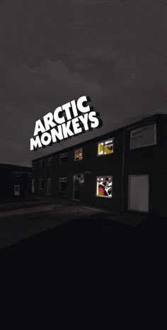 an advertisement for arctic monkeys on the side of a building at night with dark clouds in the background