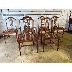 four chairs with striped upholstered seats in front of a white brick wall and floor