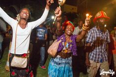 a group of people standing next to each other holding candles in their hands and smiling