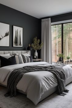 a bedroom with black walls, white bedding and large windows that look out onto the woods