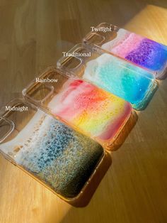 four trays with different colored powdered items in them on a wooden table top