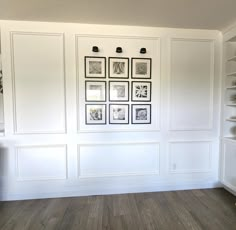 an empty room with white walls and wood flooring in the center is decorated with black and white framed pictures