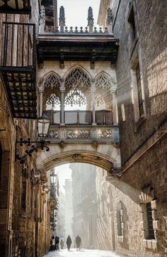 two people are walking down an alleyway in the old city with stone buildings and arched doorways