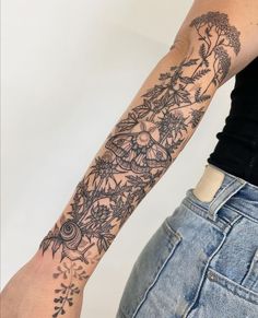 a woman's arm with flowers and leaves tattooed on the left side of her arm