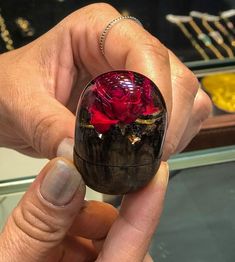 a person holding a red rose in a black box with gold trimmings on it