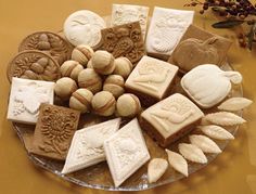 a plate filled with different types of cookies on top of a yellow surface next to a plant