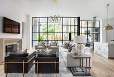 a living room filled with furniture next to a wooden floor and wall covered in windows