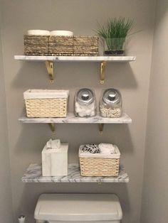 a white toilet sitting in a bathroom next to two shelves with baskets on top of it