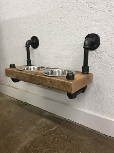 a wooden dog bowl with two metal bowls mounted to it's sides on a wall