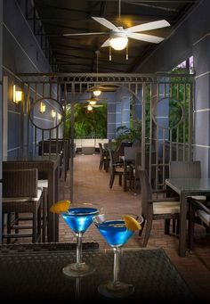 two blue martinis sitting on top of a table in front of a ceiling fan