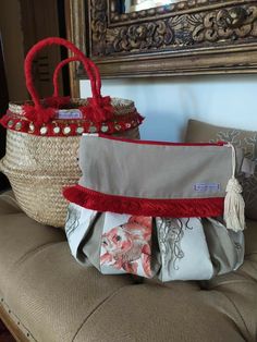 two baskets sitting on top of a couch next to each other with tassels