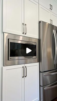 a silver refrigerator freezer sitting inside of a kitchen next to white cabinets and drawers