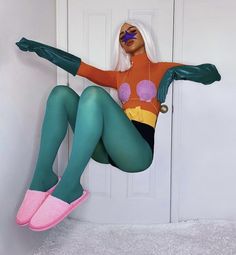 a woman in green tights and pink shoes is sitting on the door way with her legs spread out