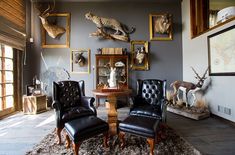 a living room filled with lots of furniture and animal heads on the wall above them