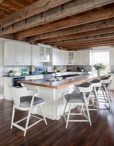 a kitchen with an island and bar stools next to it on a hard wood floor