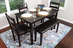 a dinning room table with four chairs and plates on the placemat, in front of two windows