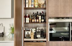 a kitchen with an oven, microwave and shelves full of bottles on the counter top