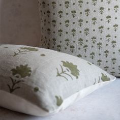 two pillows sitting next to each other on top of a white table with green flowers