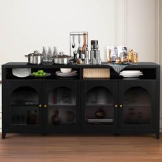 a black buffet table with plates and bowls on it in front of a white wall