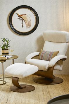 a white chair and ottoman in a room with a round painting on the wall behind it