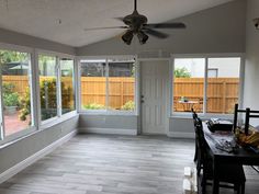 a dining room with wood floors and large sliding glass doors that lead out to the back yard