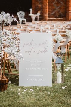 a sign that is sitting in the grass next to some chairs and flowers on it