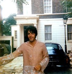 a man standing in front of a house with his hands out to the side,