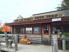 an old log store with pumpkins on the porch