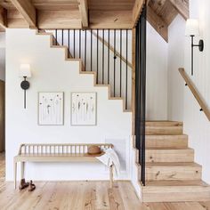 there is a wooden bench in the middle of this room with white walls and wood flooring