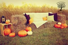 hay bales and pumpkins are arranged on the grass in front of a couch