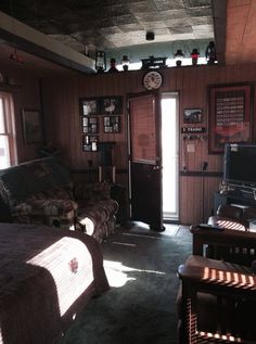 a living room filled with furniture and a flat screen tv sitting on top of a wooden wall