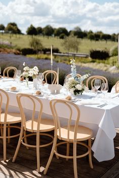 the table is set with white linens and flowers