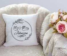 a white pillow sitting on top of a chair next to a bouquet of pink flowers